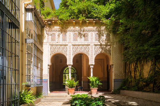 Beautiful moorish garden Ryad (Riad) with water feature, golden sunlight and arch and column entrance. Vibrant summer green colours and light. Indoor walled gardening. No people copy space