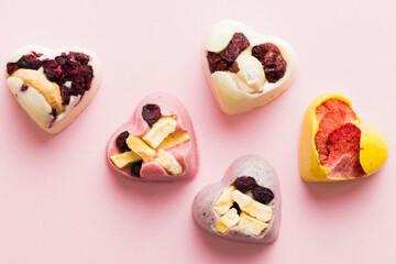 chocolate sweets in the form of a heart with fruits and nuts on a colored background. top view with space for text, holiday concept