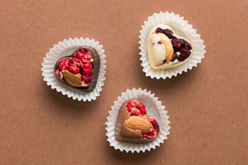 chocolate sweets in the form of a heart with fruits and nuts on a colored background. top view with space for text, holiday concept