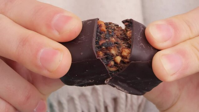 Unrecognizable woman hands breaking chocolate candy with nuts