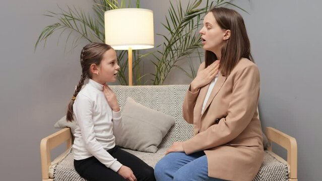 Teacher for speech improvement. Professional speech therapist. Childhood language education. Speech sound correction. Stuttering girl and speech therapist doing exercises during private lesson at home