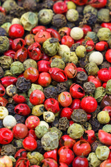 Top view of a mix of red, green, black, gray and white peppercorns.