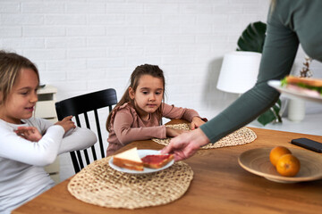  Mom brings breakfast to the table, spreading joy as the girls eagerly await the morning feast.