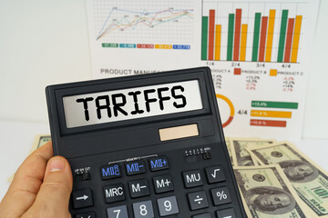 On the table there are financial reports, dollars, in the hands of a calculator with the inscription - Tariffs
