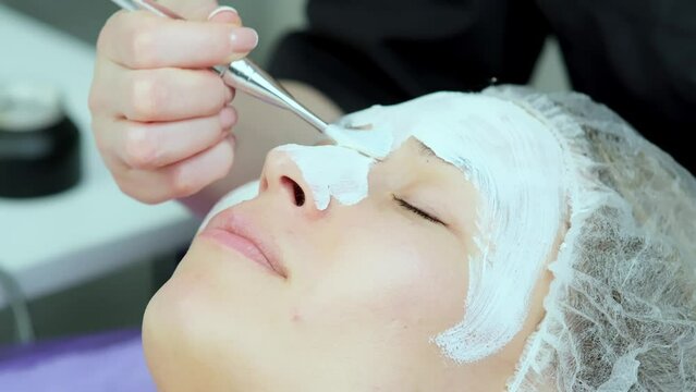 Cosmetological face mask. A cosmetologist applies a cosmetic mask in a professional beauty salon. Concept of cosmetology services.