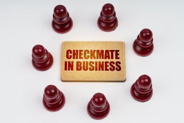 On a white background, pawns stand around a sign with the inscription - Checkmate in Business