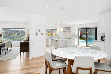 Modern dining area featuring a sleek white table surrounded by stylish gray chairs, adjacent to a