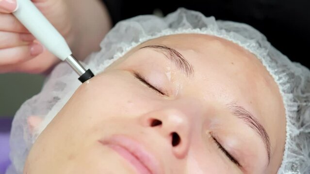 Hardware procedure in cosmetology. Close-up. Non-surgical facial skin lifting in a beauty clinic. A cosmetologist, a cosmetologist, moves a manipulator over the face. microcurrent treatment.