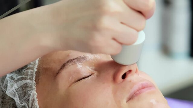 Hardware procedure in cosmetology. Close-up. Non-surgical facial skin lifting in a beauty clinic. A cosmetologist, a cosmetologist, moves a manipulator over the face. microcurrent treatment.