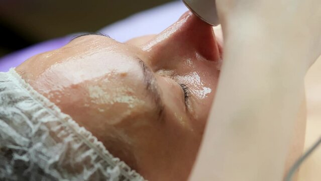 Hardware procedure in cosmetology. Close-up. Non-surgical facial skin lifting in a beauty clinic. A cosmetologist, a cosmetologist, moves a manipulator over the face. microcurrent treatment.