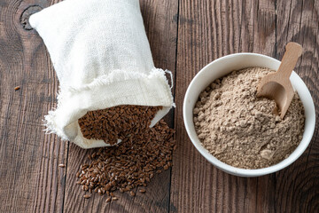 Flax seeds in a canvas bag and flaxseed flour in a bowl. Background with gluten-free alternative...