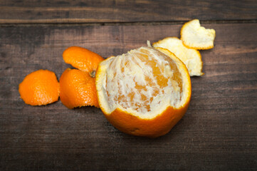 Mandarin partly peeled on a wooden board. Close-up texture of an peeled ripe sweet tangerine fruit.
