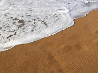 waves of foamy sea water on golden sand. Nature beach background with copy space. Relaxing vacation concept