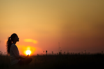 femme en position de lotus, dans la nature, au moment du lever du soleil en méditation. Espace négatif pour texte copyspace