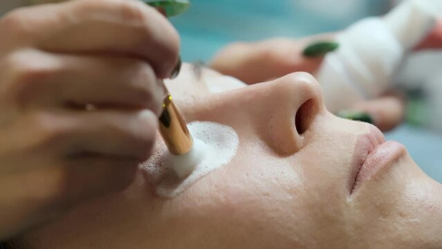 Close-up of washing and degreasing eyelashes before lamination or eyelash extension procedure. Makeup artist and client of a beauty salon.