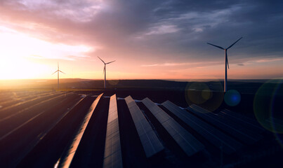 Solar panels park and wind turbines at sunset.Windmill turbines generating green energy...