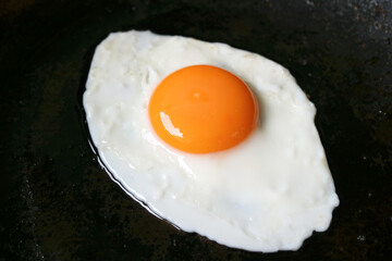 Closeup of a sunny side up egg being fried in a pan	