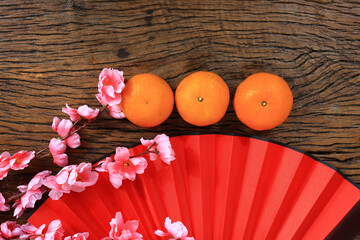 red fan and orange on a wooden background, a Chinese New Year celebration concept