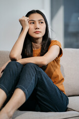 Obraz premium Sad and depressed young female sitting on the sofa, sad mood, feel tired, lonely and unhappy concept.