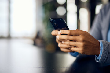 Close-up photo of a black female using a mobile phone, sending some messages.