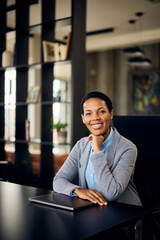 Fototapeta premium A smiling African woman posing for the camera while sitting at the office.