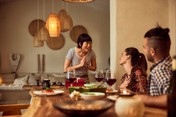 An Asian woman looking thankful for the gift from her friends.