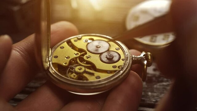 Watchmaker holds the vintage pocket watch. Mechanical watch repair. Starting the watch mechanism