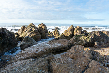 Rocks on the beach and sea waves on a sunny day in Porto, Portugal.