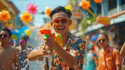 Close up happy Young man asian having fun using water gun During the Songkran Festival on Khaosan Road, Bangkok, Thailand - obrazy, fototapety, plakaty