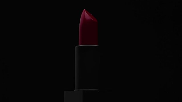 Rotation around its axis of rich, isolated bright red lipstick in a dark case on a black background as a presentation of women's cosmetics. Product display concept to maintain style and fashion