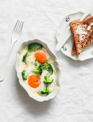 Delicious breakfast, brunch - baked eggs with broccoli and mozzarella and toast with butter on a light background, top view