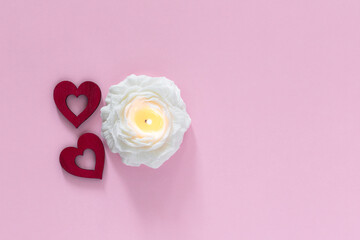 Red hearts and candle in flower shape on pink background. Valentine day and love concept. Top view with copy space for text.