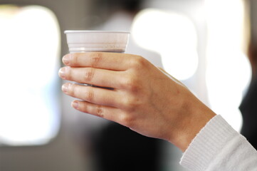 Female hand of woman drinking a cup of coffee in a recycled plastic cup.