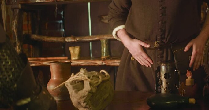 Knight changes loot on coins at old merchant shop closeup. Surprised seller gives purse with money for battle trophies of assassin in store. Medieval life