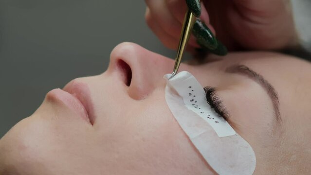 Close-up of eyelash extension procedure. Work process of a professional beauty technician lengthening women's eyelashes. False eyelashes. Eyelash extensions close-up. 