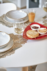 Elegant dining table setting with wine glasses, plates, and a tray with bread and dips.