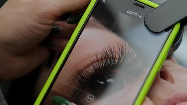 Close-up of a phone taking pictures of a client's eyes and eyelashes in a beauty salon. The concept of cosmetic services and a great result after the procedure