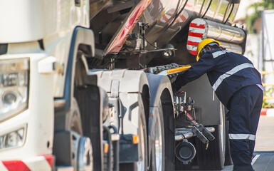 A professional mechanic in safety gear is fixing a heavy-duty commercial vehicle on a sunny day..