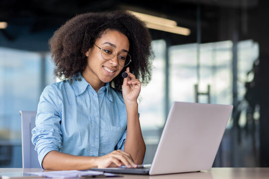A woman is using a laptop computer on a desk, surrounded by office supplies as a white-collar worker.