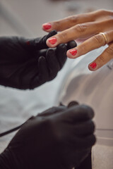 Manicurist applying red polish to client's nails.