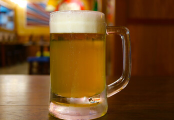 Closeup of a glass of chilled draft beer isolated on wooden table