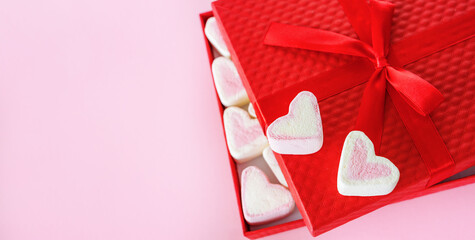 Red gift box with marshmallows in the shape of hearts on a pink background with copy space. Valentine's Day, Mother's Day, Father's Day, Wedding. Sweet confectionery product. Symbol of love
