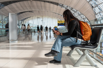 Woman backpacker traveler at airport hold smart phone device while waiting her plane at the airport...