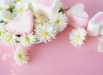 Pink marshmallows in the shape of a heart and white flowers on a pink background with copy space und bokeh. Valentine's Day, Mother's Day, Father's Day, Wedding. Sweet confectionery product.