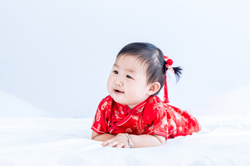 Chinese New Year concept, cute happy little girl in Chinese dress sitting in white living room. Cute Asian baby sitting in white living room, Chinese New Year concept.