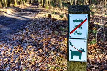 Signs indicating: dogs on leash and cars, bicycles and motorcycles prohibited, pedestrian path on...