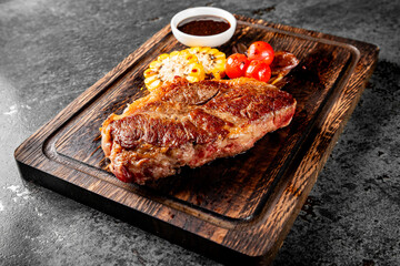 Grilled Ribeye Steak on wooden board, prime cowboy steak on dark background