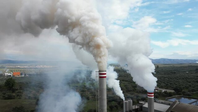 atmospheric pollution and emission of combustion fumes gas released into the air from a factory - chimney emits fine dust smog - Climate change and global warming concept - flue drone aerial view  