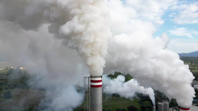atmospheric pollution and emission of combustion fumes gas released into the air from a factory - chimney emits fine dust smog - Climate change and global warming concept - flue drone aerial view  