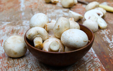 White mushrooms in a wooden bowl close-up view 